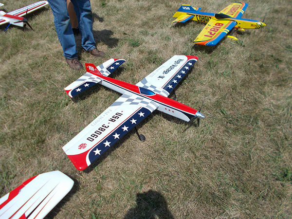 Model airplanes on grass, one red, white, and blue with stars.