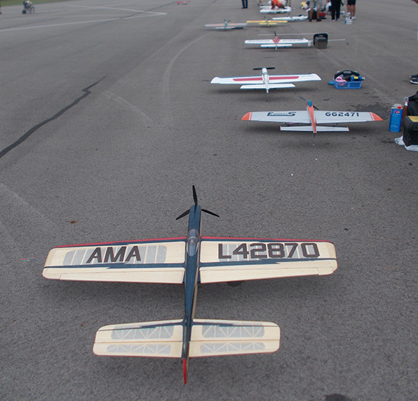 Row of model airplanes on a tarmac, preparing for flight.