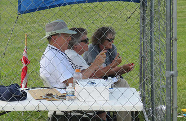 Three people sitting behind a fenced table, observing an event.