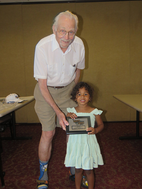 Elderly man and young girl smiling holding an award together.