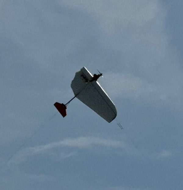 Remote-controlled glider flying in a cloudy sky.