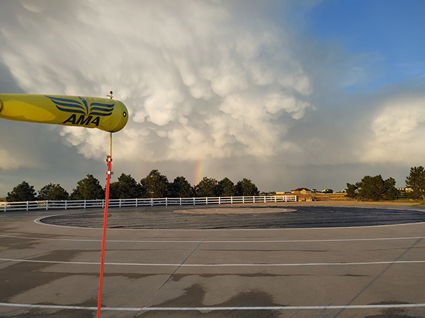Circular helipad with distant rainbow and dramatic clouds.