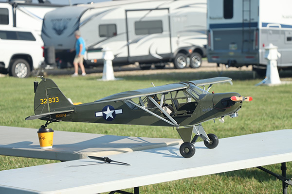 Model airplane on a table outdoors with RVs in the background.