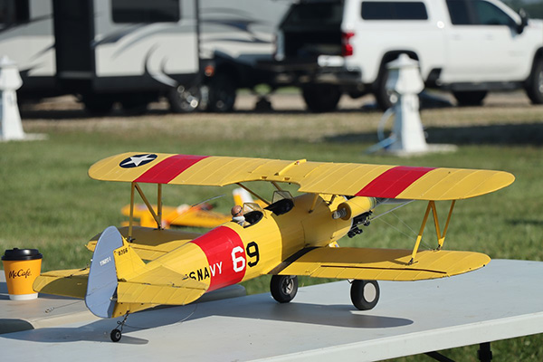 Yellow model biplane with red stripes on a table outdoors.