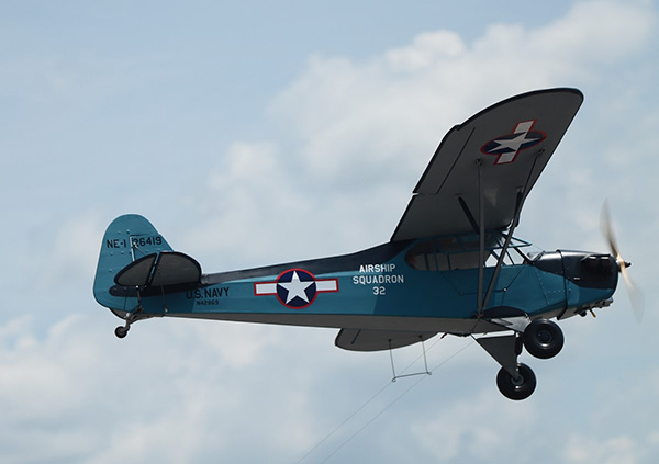 Vintage blue military aircraft flying in a cloudy sky.