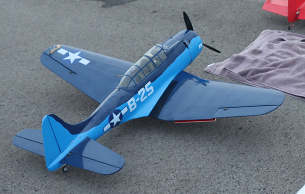 Blue model plane with "B-25" and star emblems displayed on pavement.