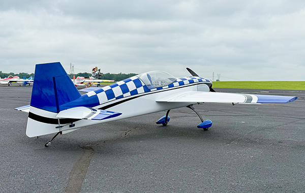 Aerobatic plane with blue and white checkered pattern on runway.