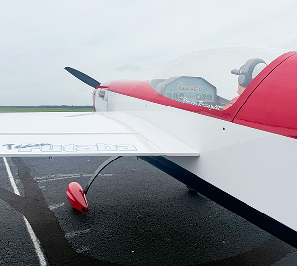 Red and white airplane on a tarmac under a cloudy sky.