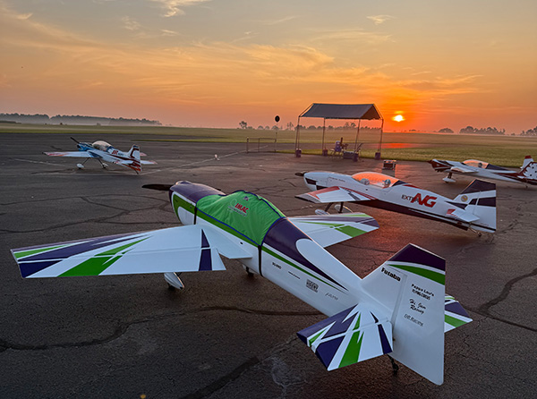 Airplanes parked on an airfield at sunrise, with colorful markings.