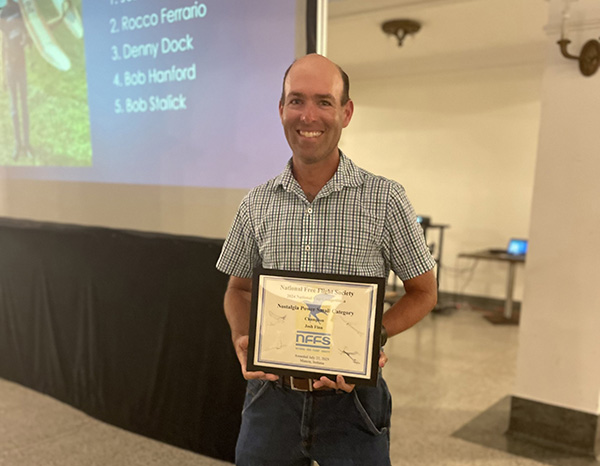 Man smiling and holding framed certificate indoors.