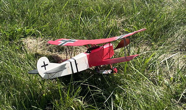 Toy biplane with red wings on green grass.
