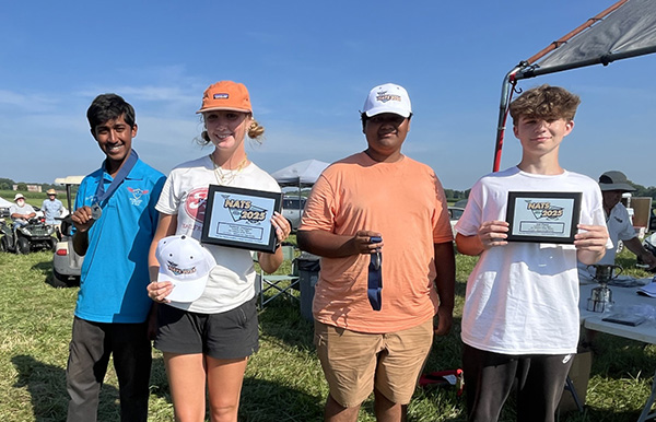 Four people outdoors holding awards and smiling.