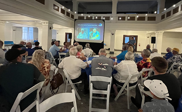 Group of people watching a presentation in a large room.