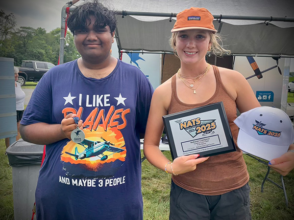 Two people at an event, holding a medal and a framed award.