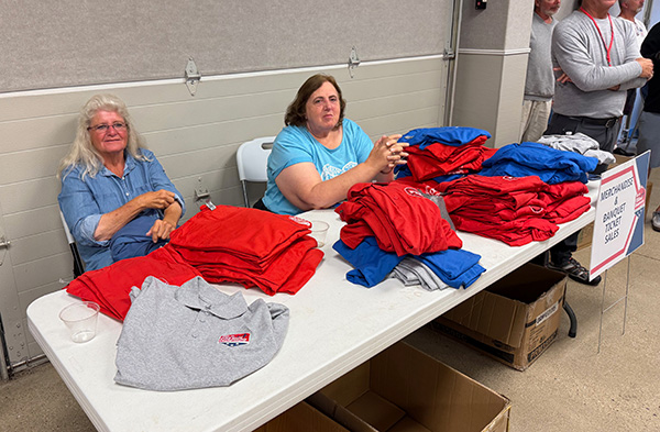 Two people seated at a table with folded red and blue shirts.