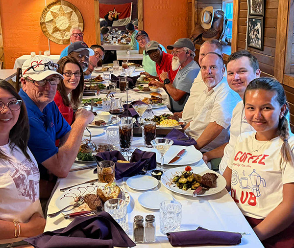 Group of people smiling around a restaurant table with food.