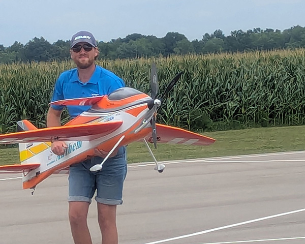Man holding large model airplane on airstrip.