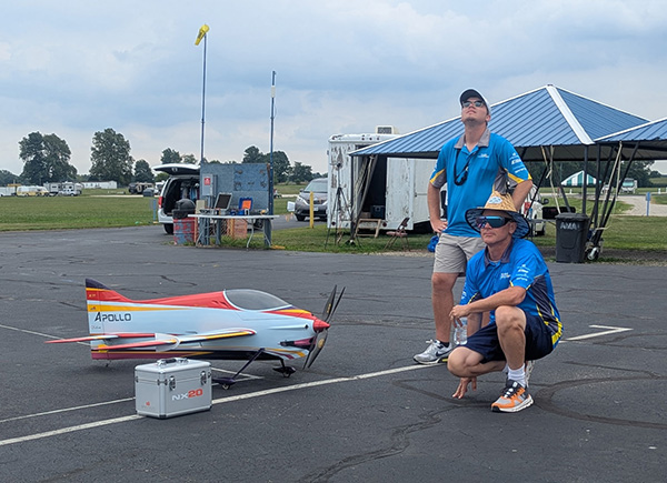 Two people beside a large model aircraft on an airfield.