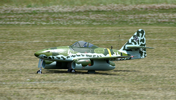 A small, camouflaged model jet on grass.