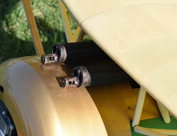 Yellow biplane wing with exposed machine guns.