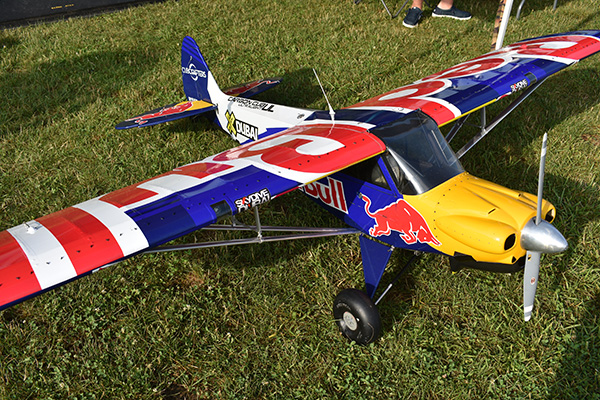 Red and blue model airplane with a yellow nose on grass.