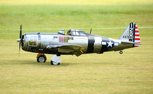 A small-scale model of a WWII fighter plane on grass.