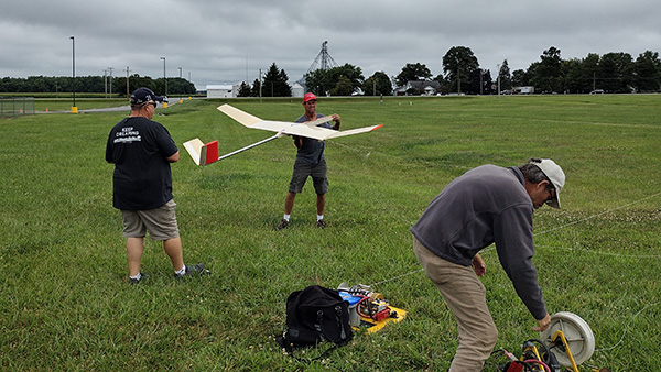 Three people in a grassy field with a large model airplane.