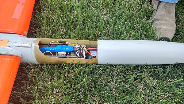 Model airplane wing opened to show wiring and electronics on grass.