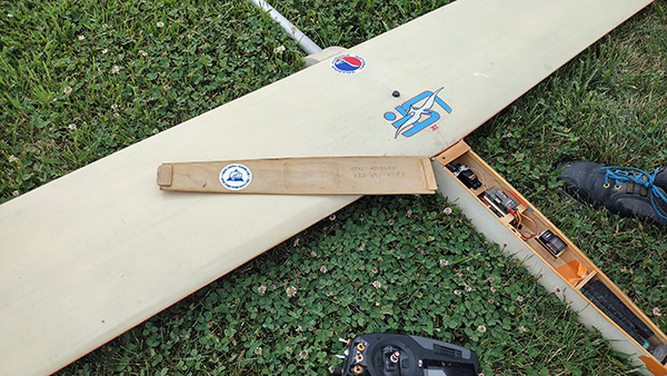 Model airplane on grass with open battery compartment.