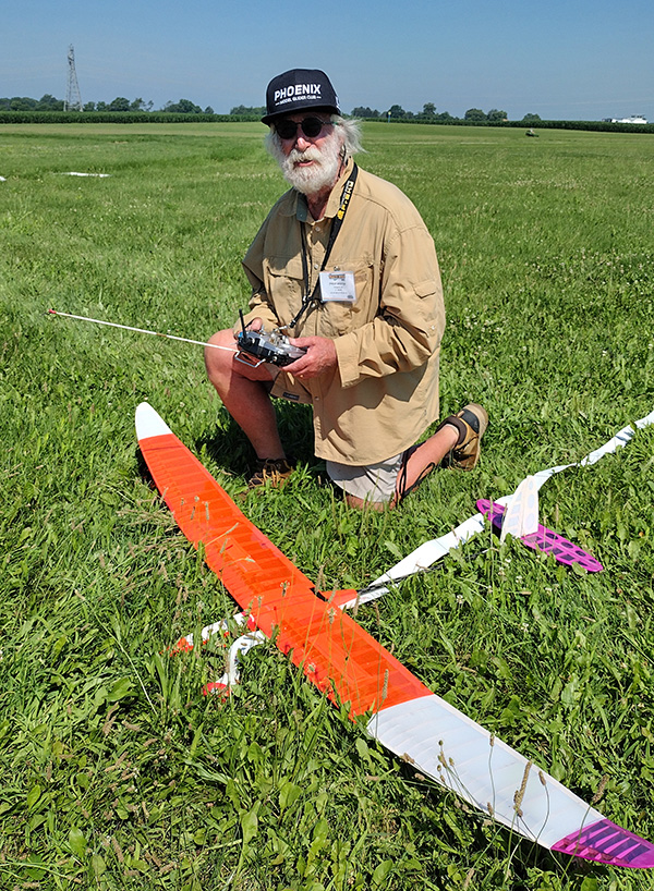 Man operating model glider in grassy field.