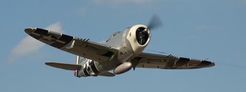 World War II-era fighter plane flying in clear sky.