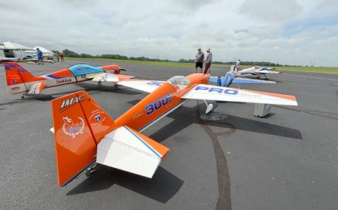 Model airplanes lined up on a runway, with one prominently orange and blue.