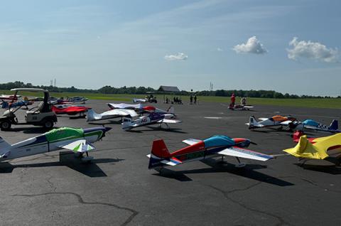Model airplanes on an airfield, people gather in the background.
