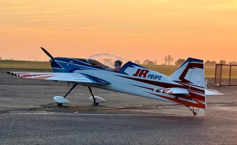 Small propeller plane on tarmac at sunset.