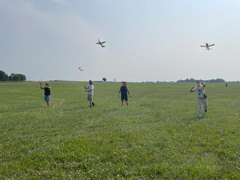 Group flying model airplanes in a field.