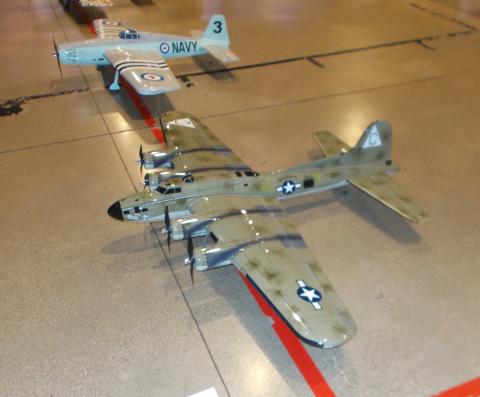 Two model military aircraft on a floor, one labeled "NAVY" in the background.