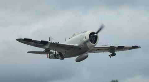 A vintage fighter plane flying in a cloudy sky.