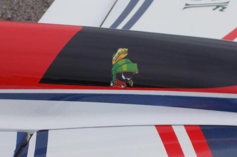 Cartoon Martian character on a red, black, and white airplane surface.