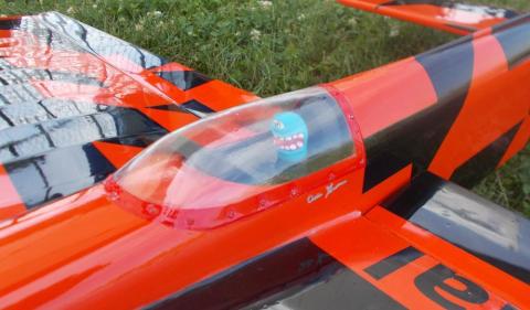 Orange and black model airplane cockpit with a blue smiling toy inside.