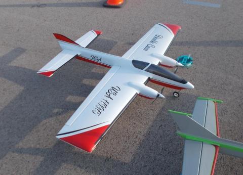 Remote control airplanes with red, white, and black detailing on a paved surface.