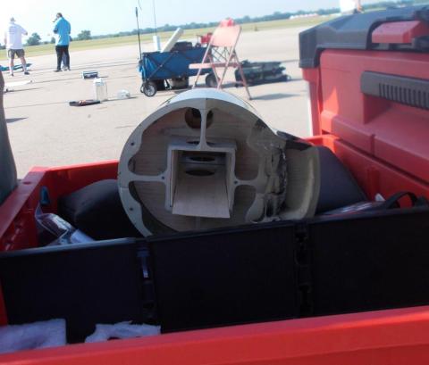 Rocket component in a red storage bin, outdoor setting.