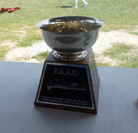 Silver trophy cup with engraved base on a table outdoors.