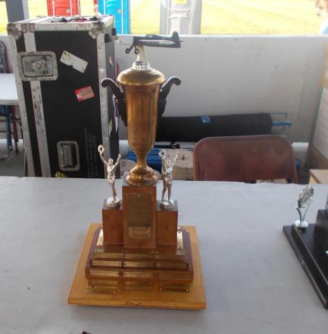 Bronze trophy with two figurines on a table in a room with equipment.