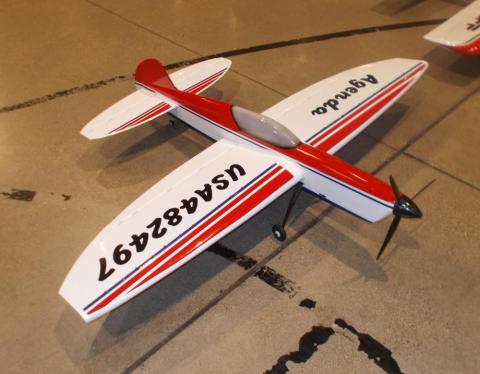 Red and white model airplane on a concrete floor.