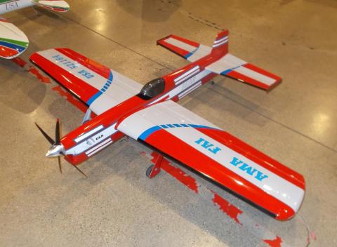 Red and white model airplane with blue accents on a polished floor.