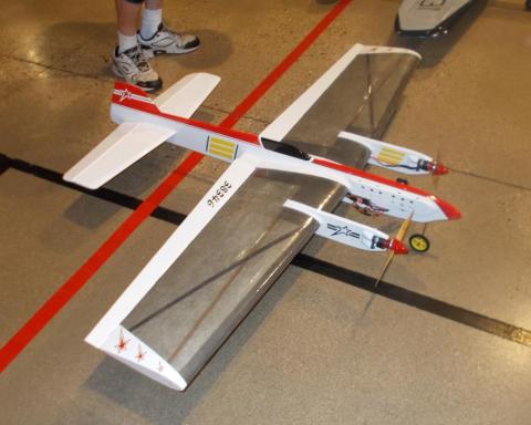 Model airplane with red and white design on a tiled floor.