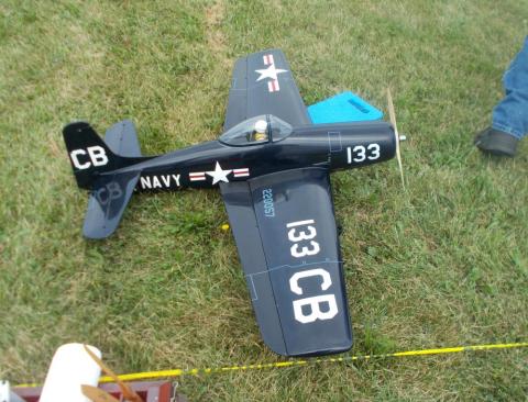 RC Navy plane model on grass, painted navy blue with white markings.