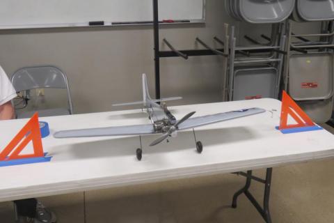 Toy plane on a table between two orange triangular stands.