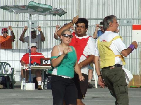 Three people wearing differently colored bibs participate in an outdoor event.