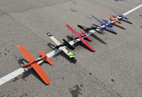 Toy planes of various colors lined up on asphalt.